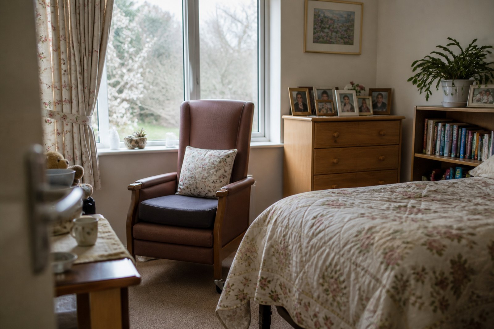 A homely care home bedroom with a supportive armchair by the window