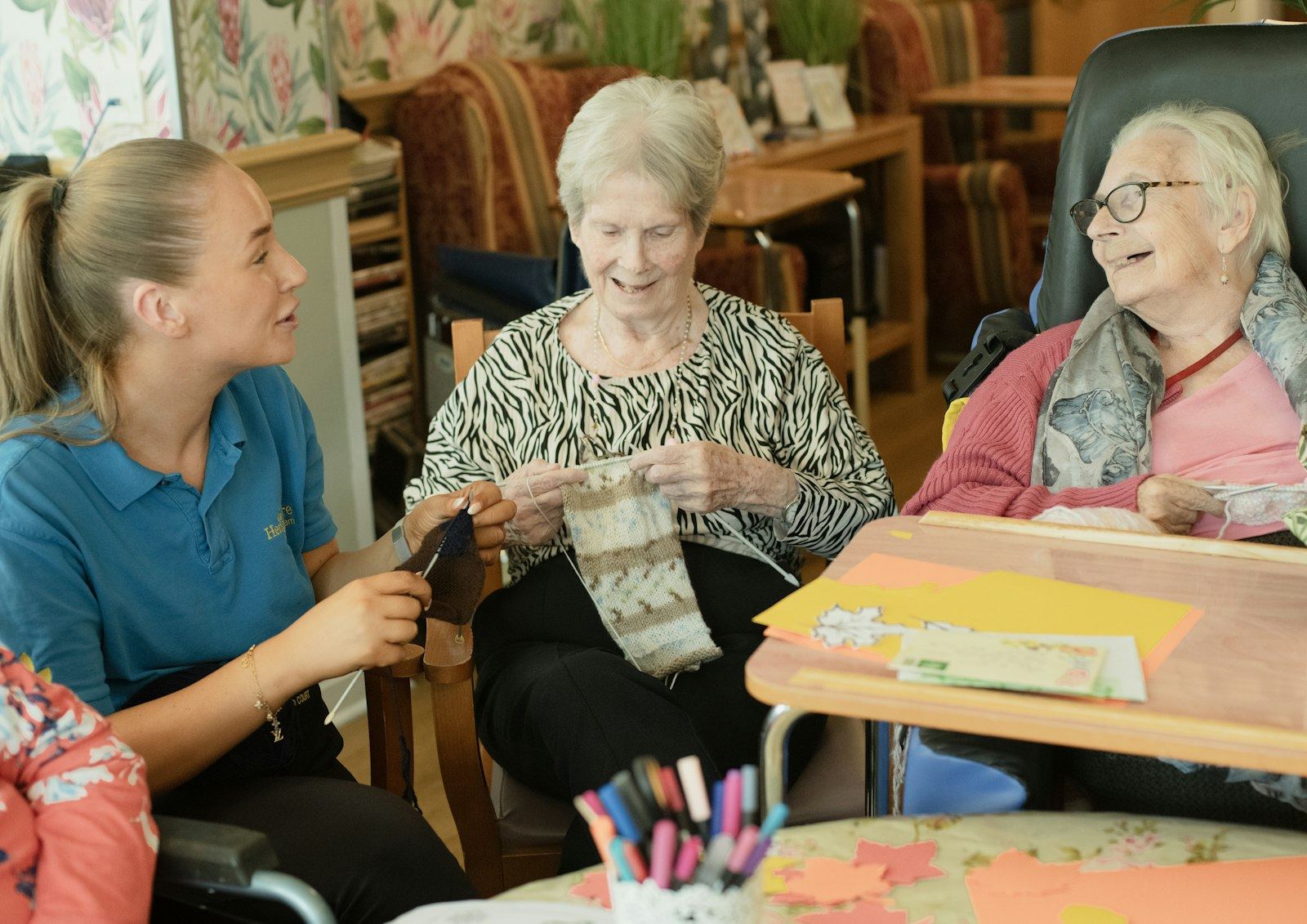 Support worker helping two older women with a knitting activity