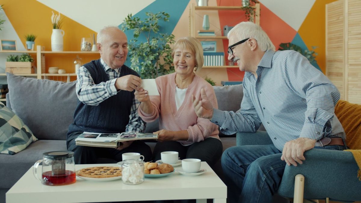 Older friends sharing a photograph over a cup of tea